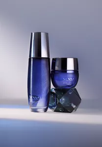 Extra Intensive Lotion auf weißer Oberfläche und Extra Intensive Cream auf facettiertem Glasblock vor stimmungsvoll beleuchtetem Hintergrund